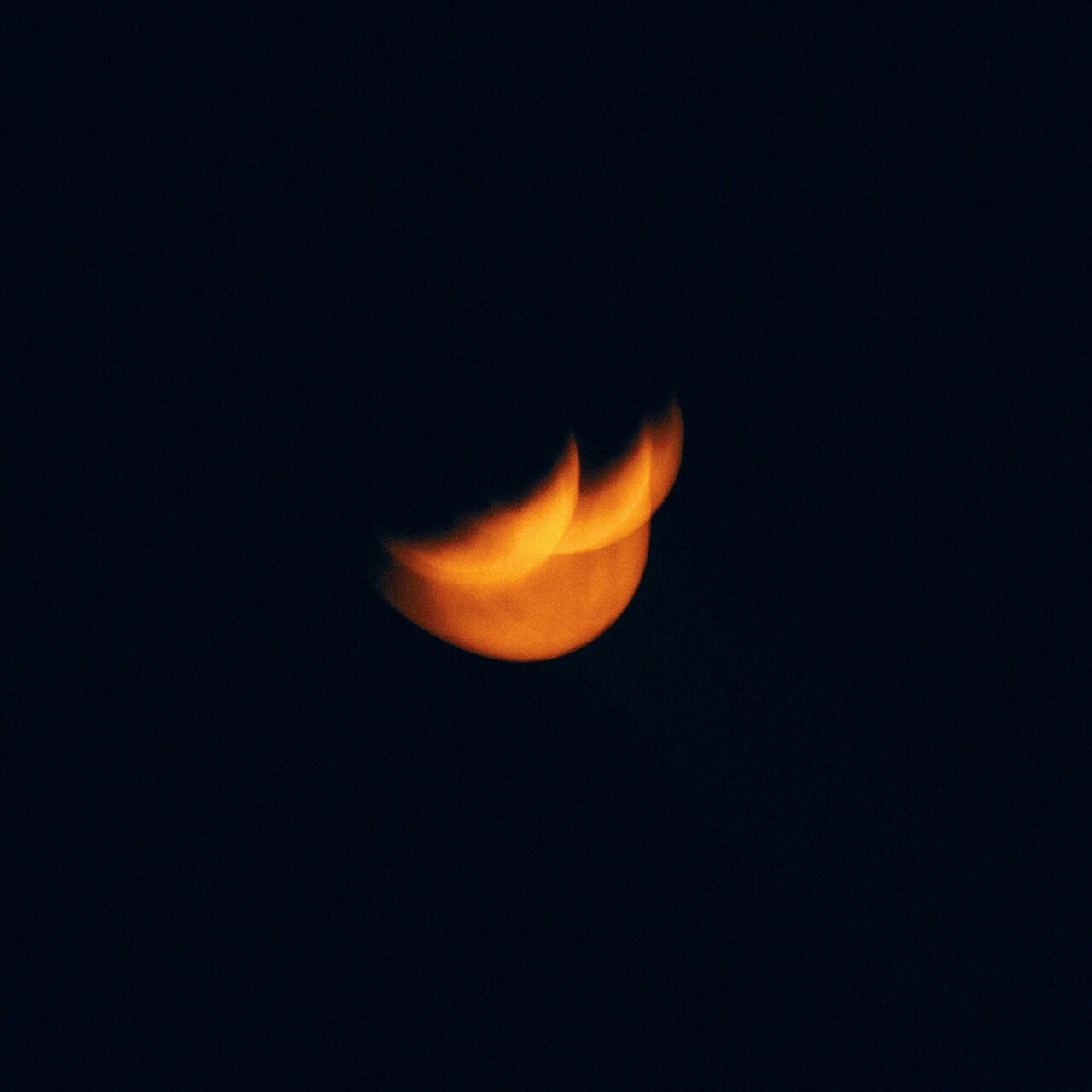 A soft orange crescent-like glow against a dark field.